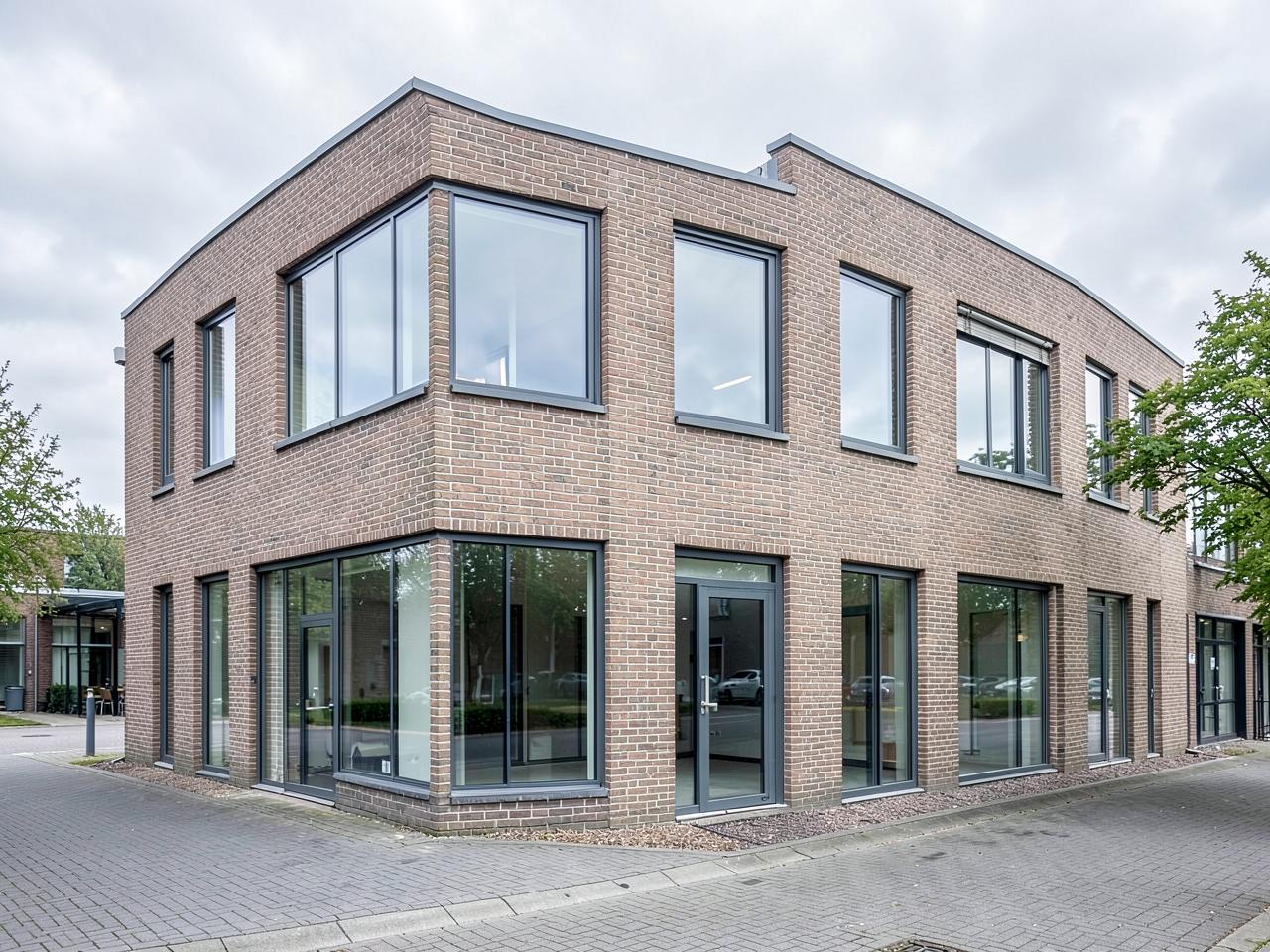 Strakke, schoongemaakte kantoorgevel van glas en natuursteen bij daglicht